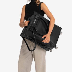 Person holding a black Travel Rolling Tote