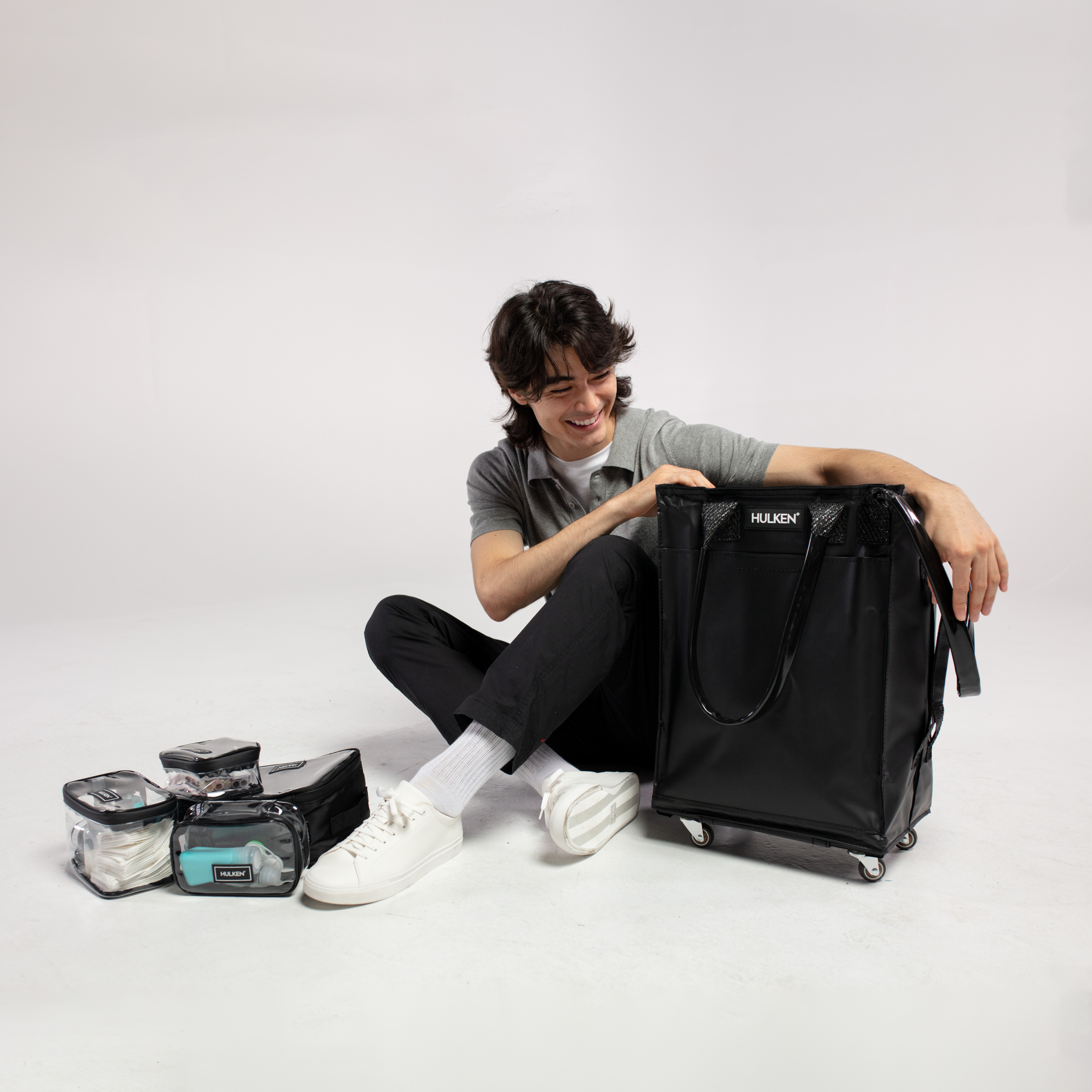 A person sitting with a black rolling bag