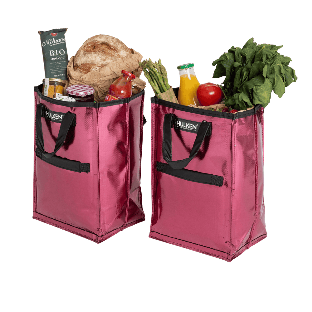 Two pink reusable shopping bags filled with groceries on a transparent background
