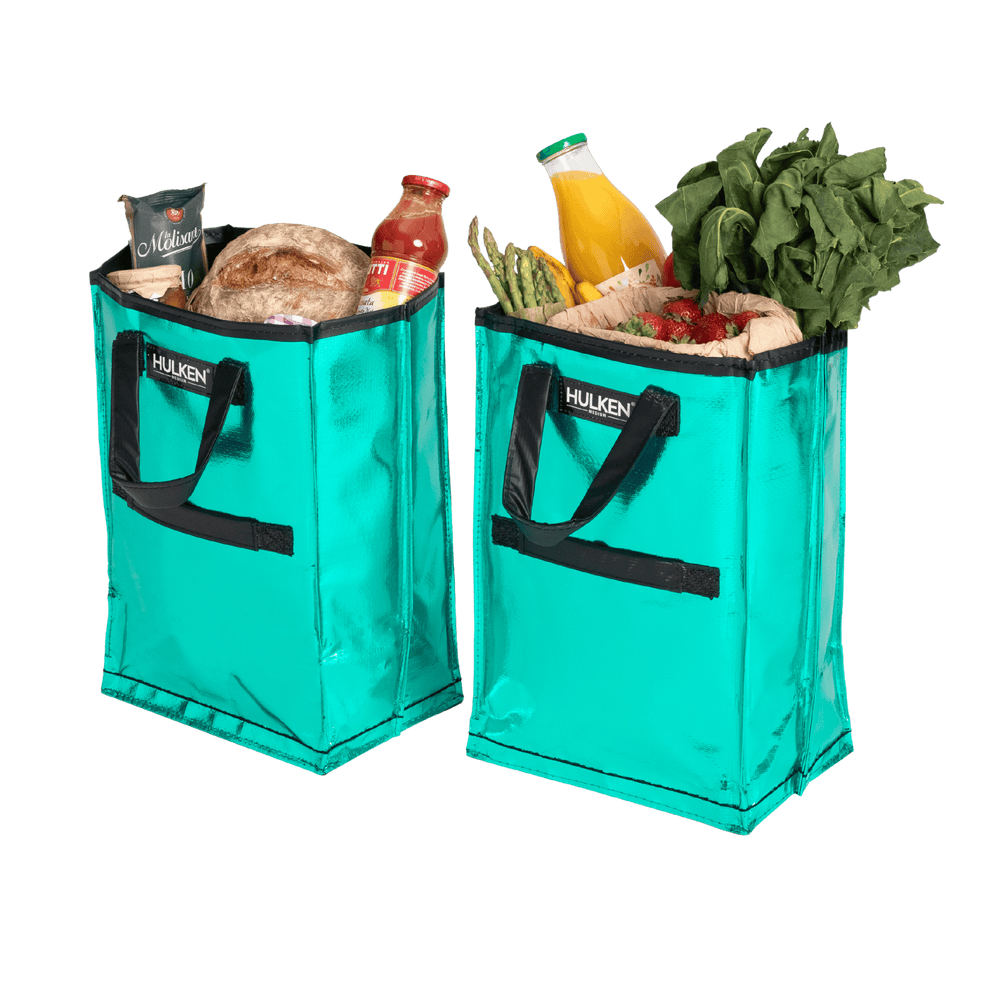 Two teal shopping bags filled with groceries on a transparent background