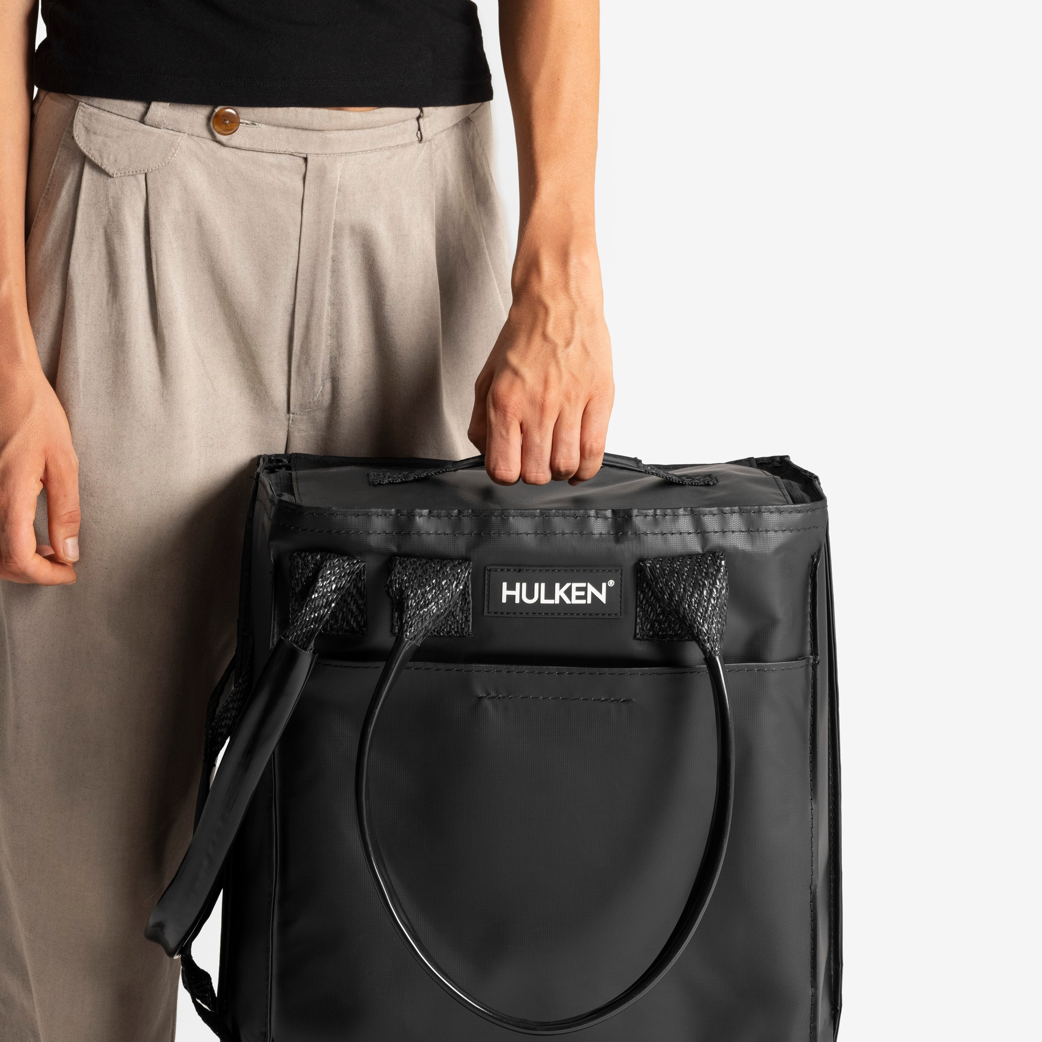 Person holding a black bag with 'Hulken' branding