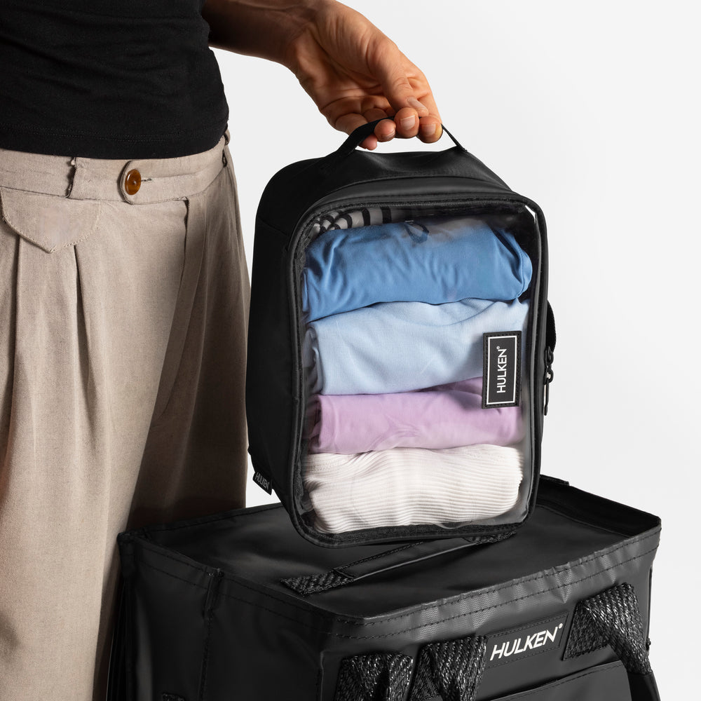 Person holding a black Hulken packing case with clothes inside