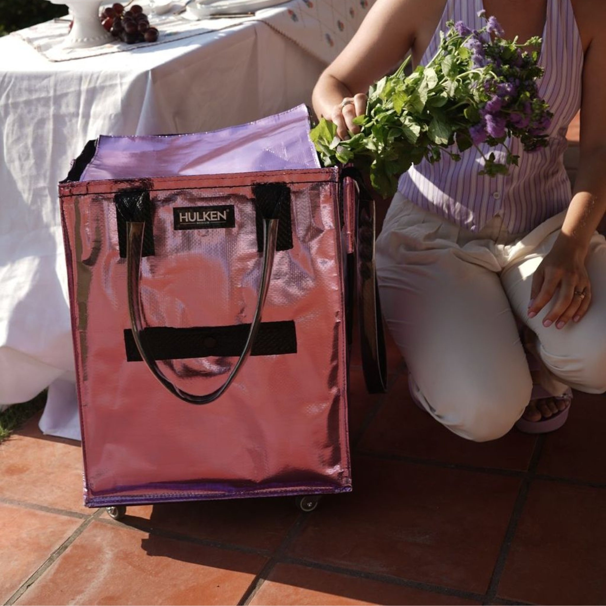 Person holding a bouquet of flowers next to a lilac tote bag